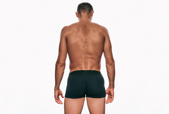 Rear view shot of muscular young man in black underwear showing